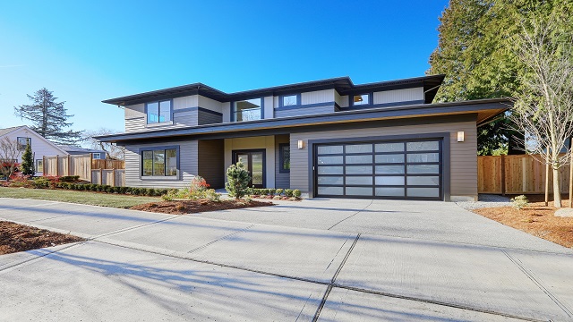 New construction home exterior with contemporary house plan features low roof brown siding and glass garage door. Northwest USA